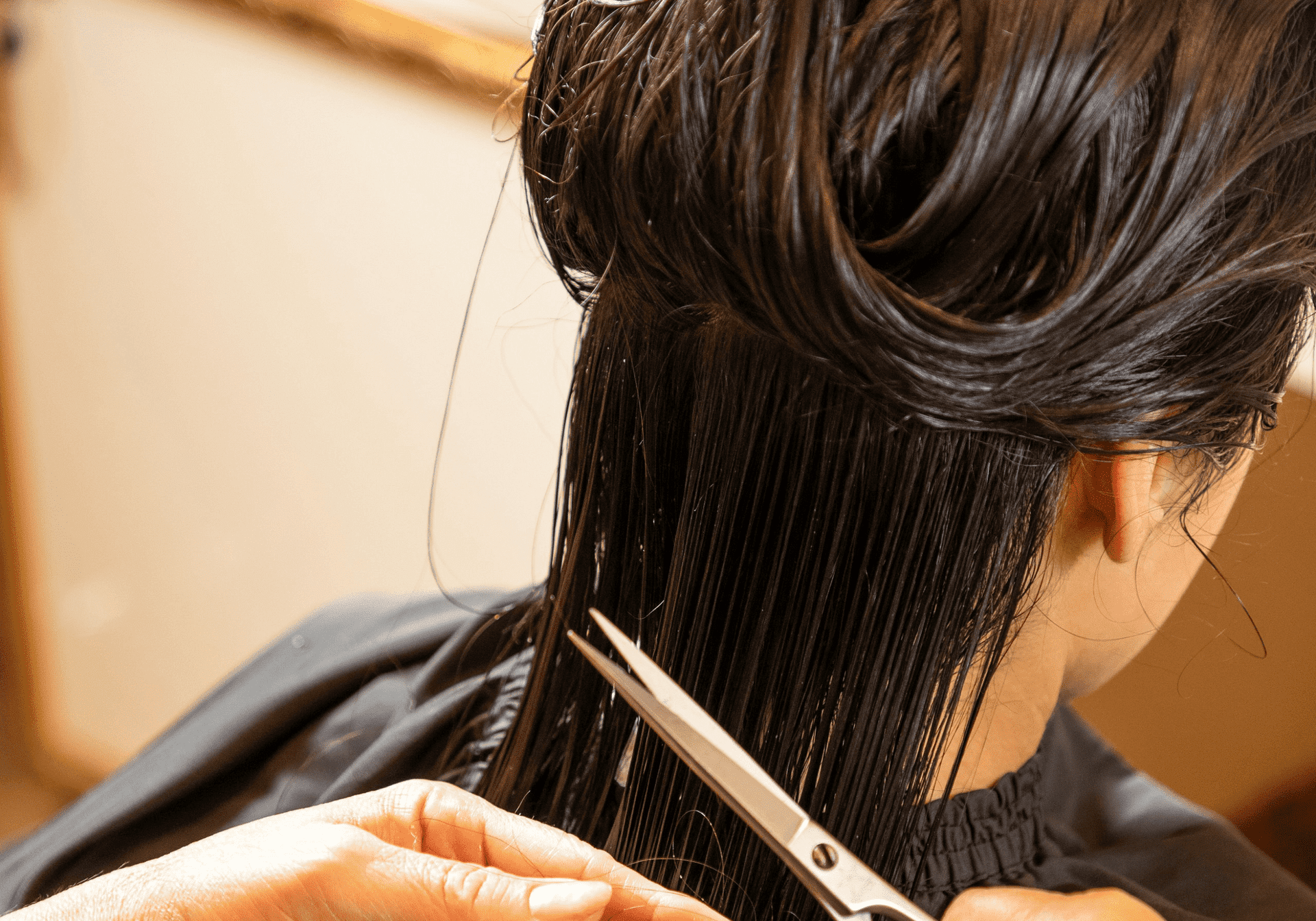 Person getting a haircut with scissors slicing through wet hair.